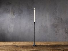 a white candle sitting on top of a wooden table next to a gray concrete wall