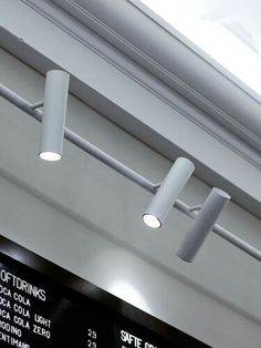 three lights are hanging from the ceiling above an airport ticket board and menus on the wall