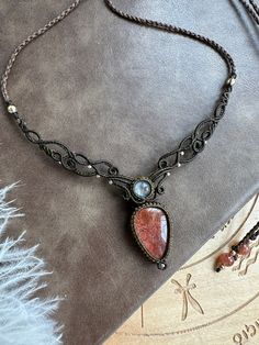 a necklace with a stone in the center on a table next to a feathery cloth