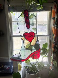 a potted plant in front of a window with a heart shaped boot hanging from it