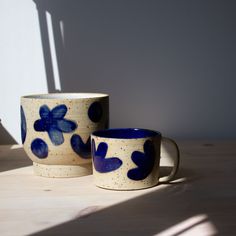 two blue and white cups sitting on top of a wooden table