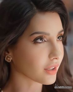 a woman with long hair and earrings on her head, looking at the camera while she is