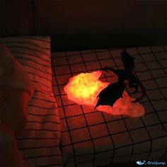 a toy bat flying through the air on top of a bed next to a red light