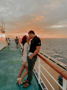 a man and woman kissing on the deck of a cruise ship at sunset or sunrise