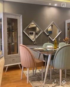 a dining room table and chairs with mirrors on the wall behind them, in front of a gray cabinet