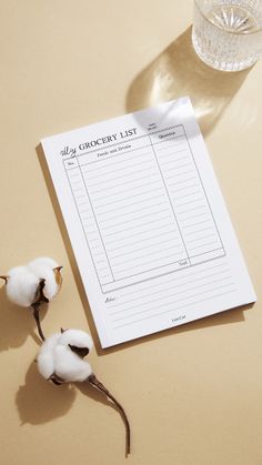 a notepad sitting on top of a table next to cotton floss and a glass of water