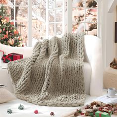 a white couch covered in a blanket next to a christmas tree