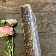 an old book next to some flowers on a wooden table with the title gray's manual of scotland