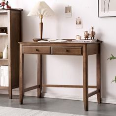 a wooden desk sitting in front of a book shelf next to a lamp on top of a hard wood floor