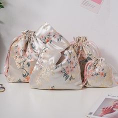 three bags sitting on top of a white table next to a magazine and flower potted plant