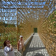 two people are standing on a bridge made out of bamboo sticks and wood planks