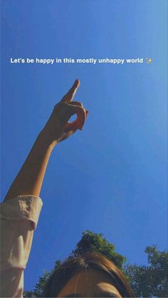 a woman pointing up at the sky with her hand in the air and trees behind her