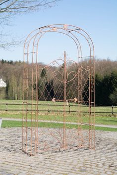 an iron sculpture in the shape of a heart on a cobblestone area near a park