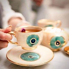 a person is holding a cup and saucer with an eyeball on the side