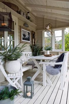 a porch with white furniture and plants on the table, potted plant next to it