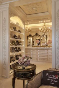 a room filled with lots of white furniture and chandelier hanging from the ceiling