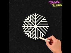 someone is drawing a snowflake on the black paper with a white marker and pencil