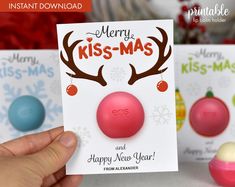 a hand holding up a christmas card with two balls and reindeer antlers on it