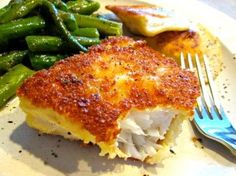 a close up of a plate of food with broccoli and green beans in the background