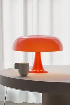 an orange lamp sitting on top of a table next to a cup and saucer