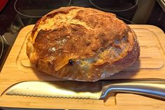 a loaf of bread sitting on top of a wooden cutting board next to a knife