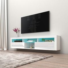 a white entertainment center with a tv mounted on it's wall and a rug in front of it