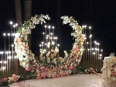 an outdoor wedding setup with candles and flowers on the ground, surrounded by tall poles