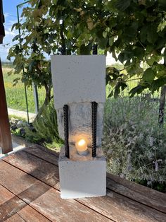 a light that is sitting on top of a wooden table in front of some trees