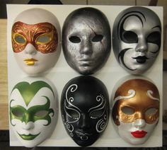 six masks are lined up in a row on a white board with black and gold designs