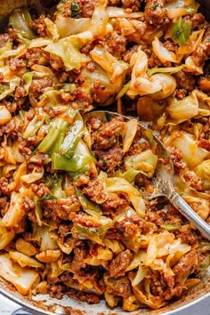 a large pot full of cabbage and meat with a spoon in the bowl next to it