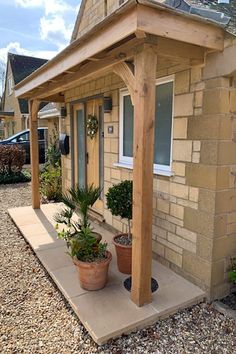 a small house with a covered porch and potted plants