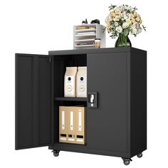 a black cabinet with two drawers and some flowers on the top one is open to show its contents