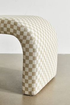 a white and brown checkered bench sitting on top of a cement floor