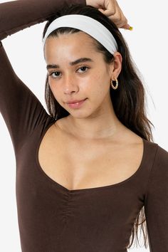 a woman wearing a brown top with a white headband on her head is posing for the camera