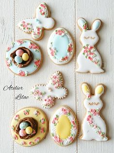 some decorated cookies are sitting on a white table with eggs and bunnies in them