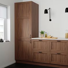 a kitchen with wooden cabinets and white counter tops, along with black lamps on the wall