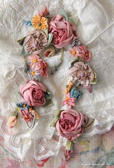 several pink flowers are laying on a white lace doily with an old - fashioned keychain in the background