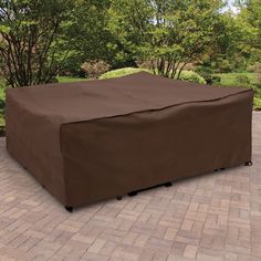 a large brown cover on top of a brick patio area with trees in the background