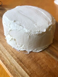 a white cake sitting on top of a wooden cutting board