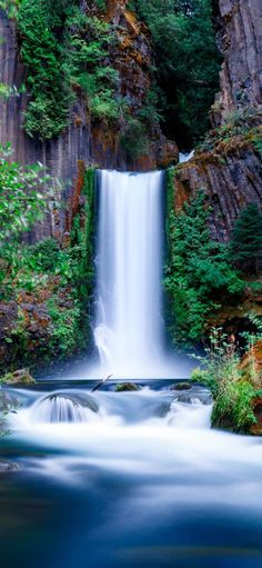 a small waterfall in the middle of a forest