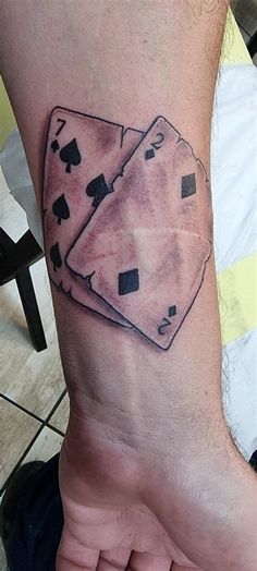 a man with a tattoo on his arm that has two playing cards on it