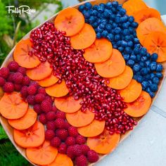 a platter filled with fruits and berries on top of a table next to plants