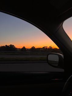 the sun is setting in the distance as seen from inside a car