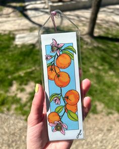 a person holding up a card with oranges on it in front of some grass