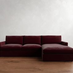 a red couch sitting on top of a hard wood floor next to a white wall