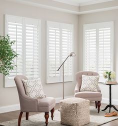 a living room with two chairs and a footstool in front of the window