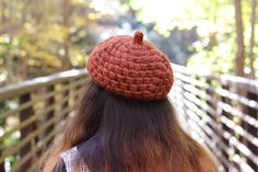 a woman wearing a red crocheted hat on top of her head while sitting on a bench