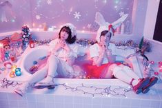 two women sitting in a bathtub surrounded by christmas decorations