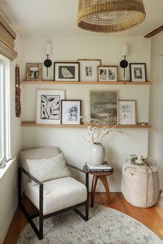 a living room filled with furniture and framed pictures on the wall above a chair in front of a window