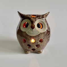 an owl figurine with glowing eyes sits on a white surface